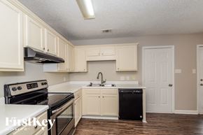 Helena house for rent - A kitchen with white cabinets and a black dishwasher.