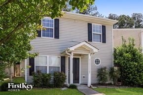 Stockbridge house for rent - A house with a grey siding and a black door is surrounded by greenery.