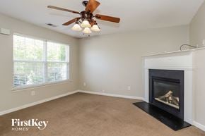 Stockbridge house for rent - A living room with a fireplace and a ceiling fan.