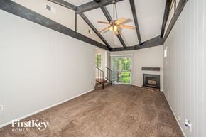 Birmingham house for rent - A spacious room with a fireplace and a ceiling fan.