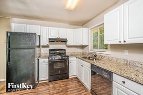 Birmingham house for rent - A kitchen with a black fridge and white cabinets.