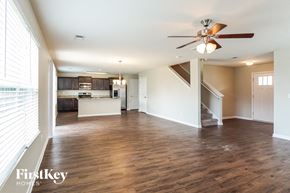 Calera house for rent - an empty living room with a ceiling fan and a kitchen