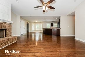 Fayetteville house for rent - an empty living room with a fireplace and a ceiling fan