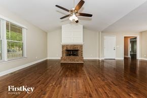 Fayetteville house for rent - an empty living room with a fireplace and a ceiling fan