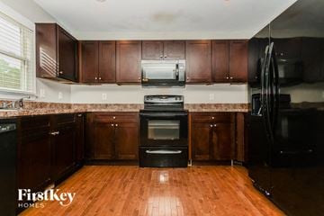 Fayetteville house for rent - a kitchen with dark wood cabinets and black appliances