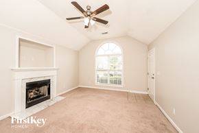 Calera house for rent - A room with a fireplace and a ceiling fan.