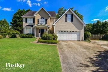 Loganville house for rent - a house with a white garage door on a green lawn