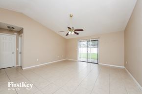 Kissimmee house for rent - A spacious room with a ceiling fan and sliding glass doors leading to a balcony.