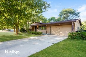 Crystal Lake house for rent - A house with a garage is surrounded by greenery.