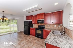 Odenville house for rent - A kitchen with red cabinets and a black refrigerator.