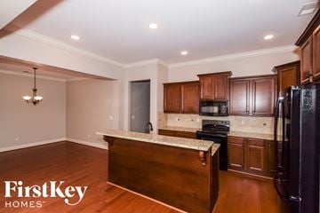 Wilsonville house for rent - a kitchen with wooden cabinets and black appliances and a granite counter top
