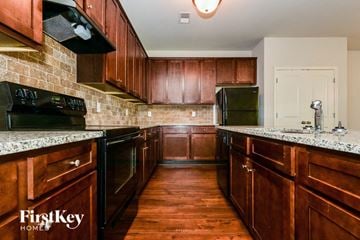 Mcdonough house for rent - A kitchen with wooden cabinets and a black refrigerator.