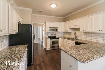 Newnan house for rent - a kitchen with marble counter tops and white cabinets