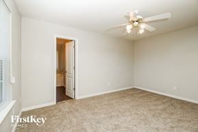 Covington house for rent - an empty bedroom with a ceiling fan and a door to a bathroom