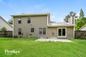 Summerville house for rent - A house with a brown roof and a white door is surrounded by a grassy area.
