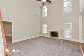 Mcdonough house for rent - A spacious room with a fireplace and a ceiling fan.