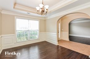 Mcdonough house for rent - A room with a chandelier, a window with blinds, and a doorway leading to another room.