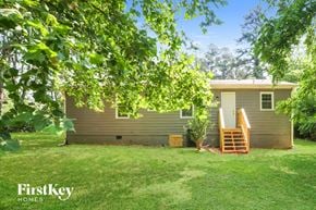 Dacula house for rent - A house with a brown exterior is surrounded by greenery.
