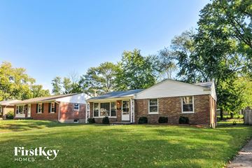 Florissant house for rent - a brick house with a green lawn and trees
