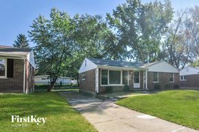 Florissant house for rent - a small brick house with a driveway and a tree