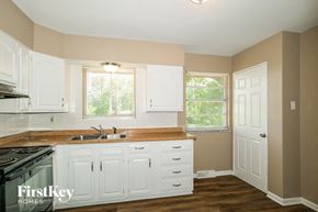 Saint Louis house for rent - a kitchen with white cabinets and a stove and a sink