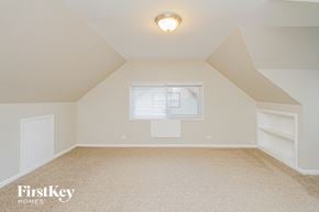 Chicago Heights house for rent - the attic bedroom of a home with a window and white shelves