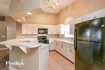 Winter Haven house for rent - a kitchen with white cabinets and a black refrigerator