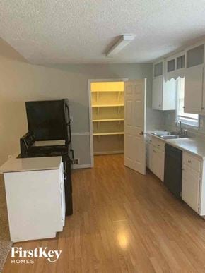 Locust Grove house for rent - an empty kitchen with a wood floor and white cabinets