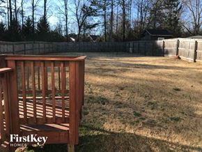 Newnan house for rent - A wooden bench is in the foreground of a grassy yard.