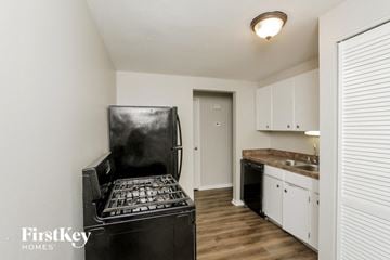 Chicago Heights house for rent - a kitchen with white cabinets and a black stove and refrigerator