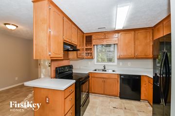 Stockbridge house for rent - a kitchen with wooden cabinets and black appliances