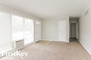 Park Forest house for rent - an empty living room with a large window and a door to a hallway
