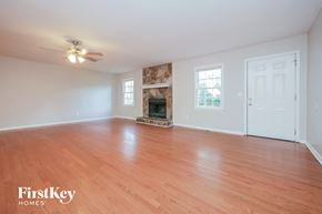 Newnan house for rent - an empty living room with a fireplace and wood flooring