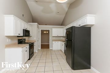 Alabaster house for rent - A black refrigerator in a kitchen with white cabinets.
