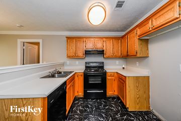 Stockbridge house for rent - a kitchen with wood cabinets and black appliances and white counter tops