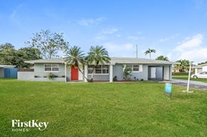 Lehigh Acres house for rent - a house with a lawn and palm trees in front of it