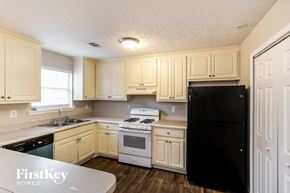 Winder house for rent - a kitchen with white cabinets and white appliances and a black refrigerator