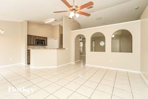 Poinciana house for rent - A spacious living room with a kitchen in the background and a fan on the ceiling.