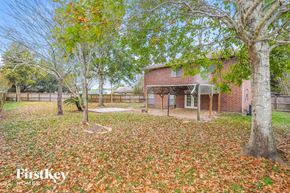 Richmond house for rent - a backyard with trees and a brick house with a fence