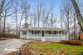 Dallas house for rent - A house with a porch is surrounded by trees.