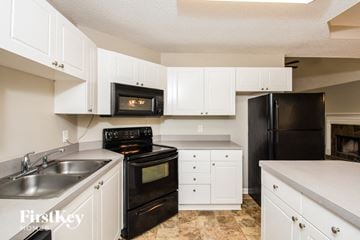 Adairsville house for rent - a kitchen with black appliances and white cabinets
