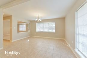 Spring house for rent - A spacious room with a chandelier and large windows.