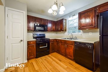 Douglasville house for rent - a kitchen with wooden cabinets and black appliances