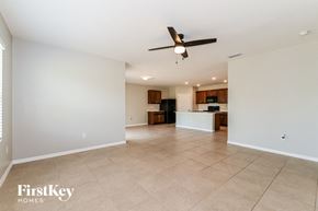 Cape Coral house for rent - A spacious living room with a ceiling fan and a kitchen in the background.