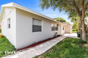 Greenacres house for rent - A white house with a red border around the windows and doors.