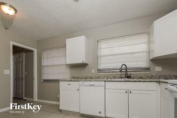 Greenacres house for rent - A kitchen with white cabinets and a granite countertop.