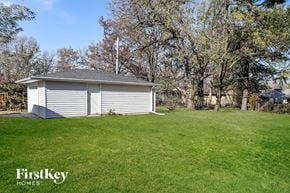 Park Forest house for rent - A small white building with a grey roof is surrounded by a grassy field.