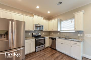 Calera house for rent - a kitchen with white cabinets and stainless steel appliances