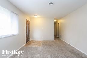 Beech Grove house for rent - A spacious room with a carpeted floor and a door on the left.