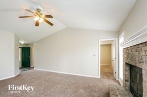 Greenwood house for rent - A room with a fireplace and a ceiling fan.